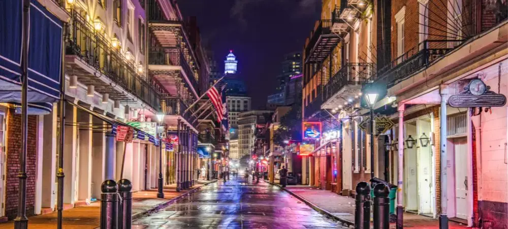 Illuminated French Quarter street in New Orleans at night with historic balconies and colorful neon lights