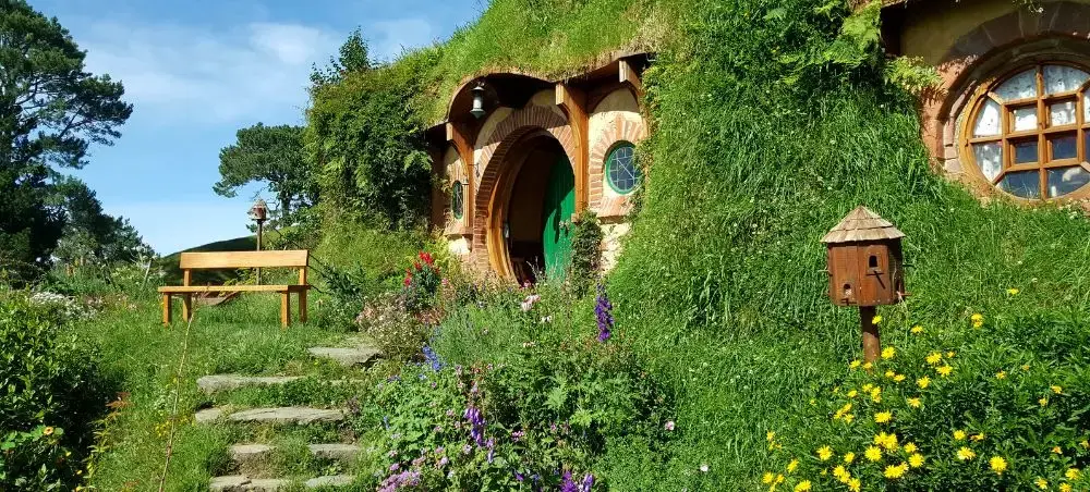 Hobbiton movie set featuring iconic hobbit hole with green door nestled in rolling hills of New Zealand