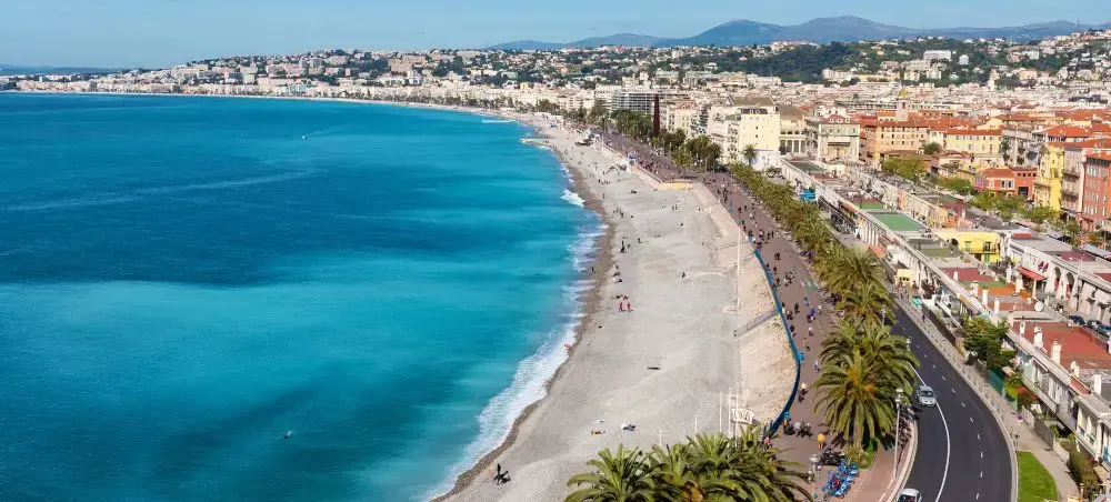 Aerial view of Nice's stunning Promenade des Anglais coastline with turquoise Mediterranean waters and palm trees