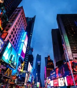 Times Square's towering skyscrapers and vibrant digital billboards illuminate the night sky in Manhattan