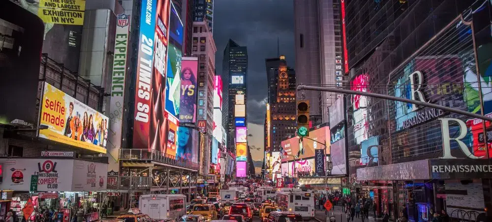 Bustling Times Square at dusk with illuminated billboards and heavy traffic showcasing NYC's vibrant energy