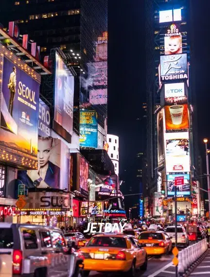 Bustling Times Square at night with illuminated billboards, yellow taxis, and crowded streets in Manhattan