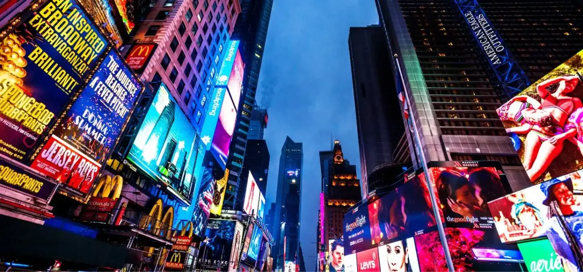 Times Square at dusk with towering digital billboards and neon signs illuminating Manhattan's iconic theater district