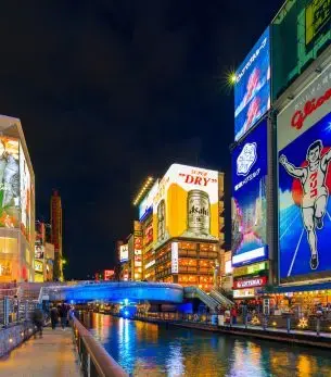 Vibrant neon signs illuminate Dotonbori district canal in Osaka at night, showcasing Japan's iconic urban entertainment quarter