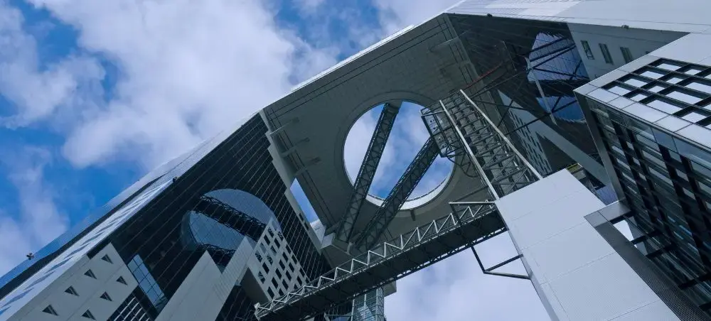 Modern Osaka skyscraper with distinctive circular architectural feature reaching toward cloudy blue sky