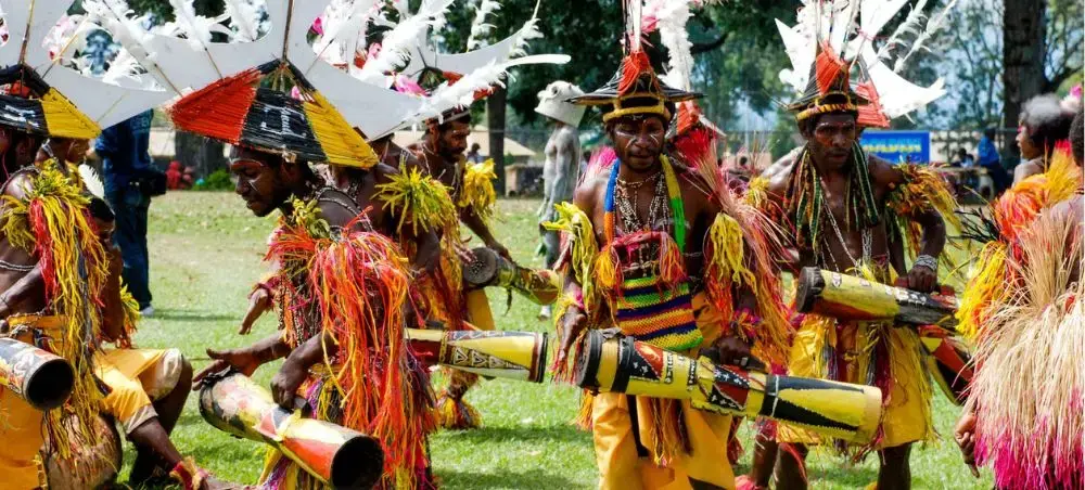 Traditional Papua New Guinea dancers in vibrant feathered costumes performing cultural ceremony outdoors