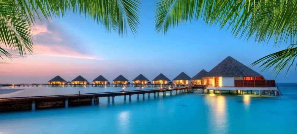 Overwater bungalows connected by wooden walkway at tropical resort in Paradise Island Bahamas at sunset