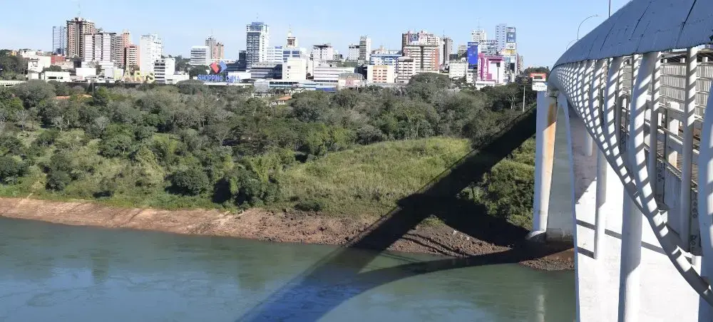 Modern bridge spanning river with Paraguay's capital city skyline and lush greenery in background
