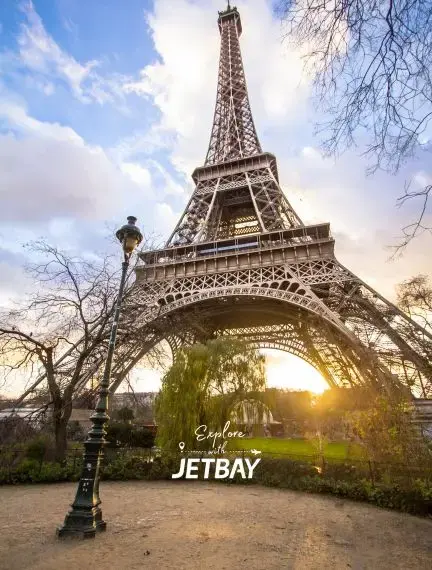Eiffel Tower at sunset with golden light streaming through its iron lattice structure in Paris France