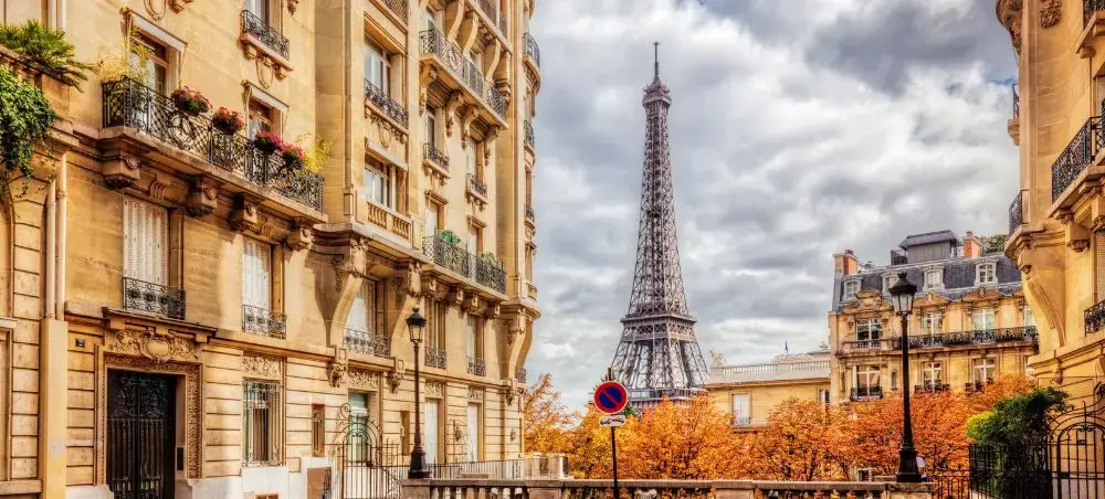 Classic Parisian street view featuring elegant Haussmann architecture with Eiffel Tower rising majestically