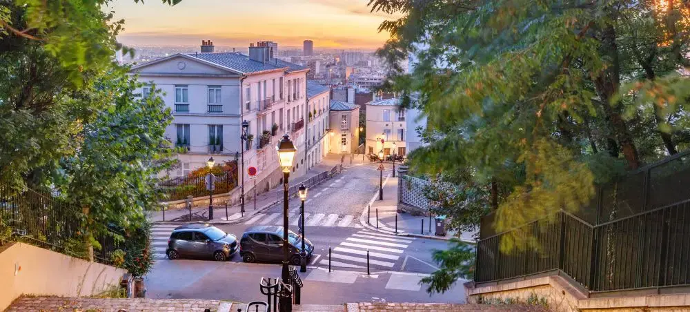 Charming cobblestone street in Montmartre Paris with historic buildings and city skyline at golden hour