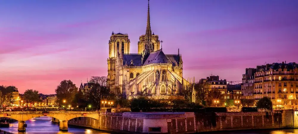 Notre-Dame Cathedral illuminated at twilight with Seine River and historic Parisian architecture