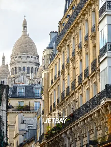 Sacré-Cœur Basilica rises above classic Parisian Haussmann buildings with ornate iron balconies in Montmartre