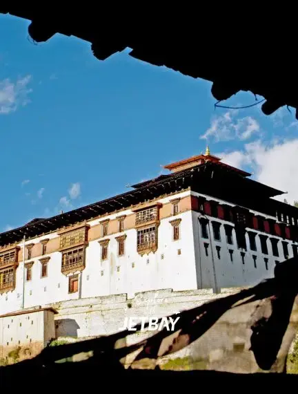 Traditional Bhutanese dzong fortress with distinctive architecture framed by cave opening in Paro valley