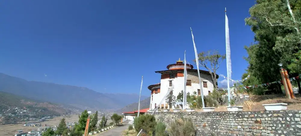 Traditional Bhutanese fortress architecture in Paro valley with prayer flags and mountain backdrop