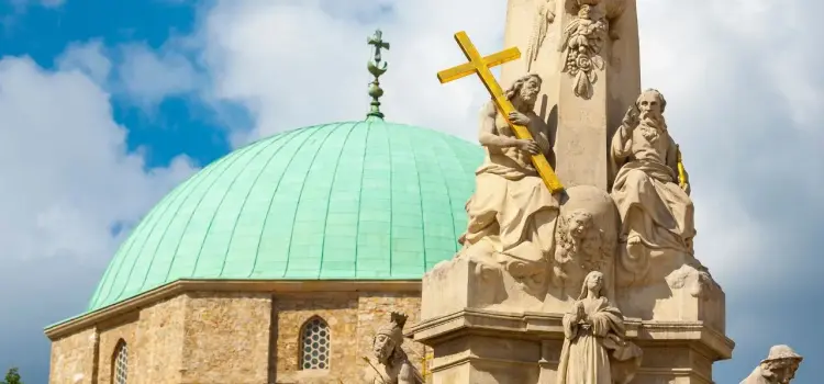 Historic baroque monument with ornate religious sculptures and green copper dome in Pecs, Hungary