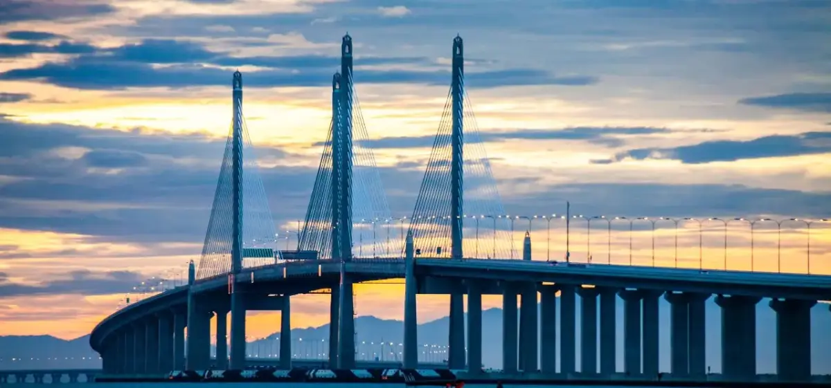 Penang Bridge illuminated at sunset with cable-stayed towers spanning across Malaysian waters