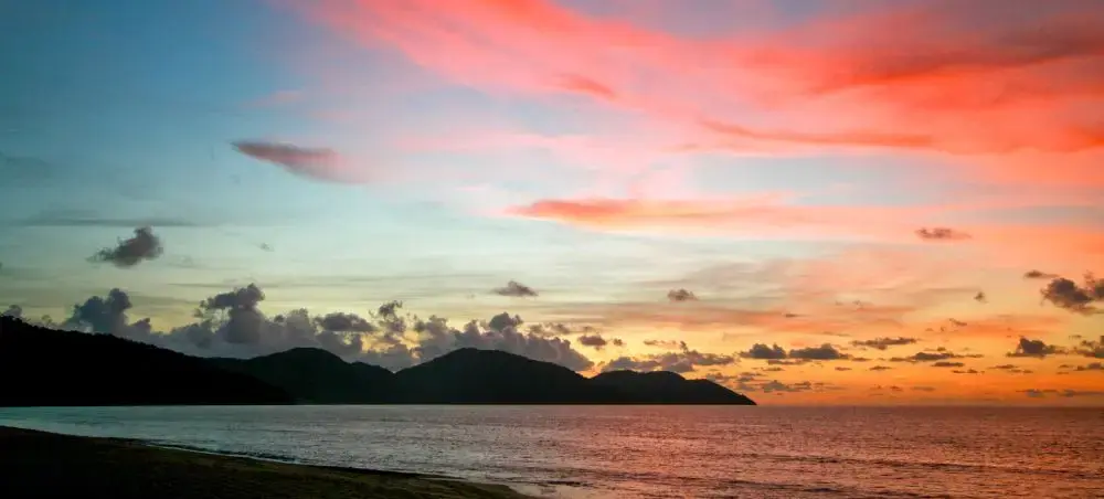 Stunning sunset over Penang coastline with vibrant orange and pink skies reflecting on calm waters