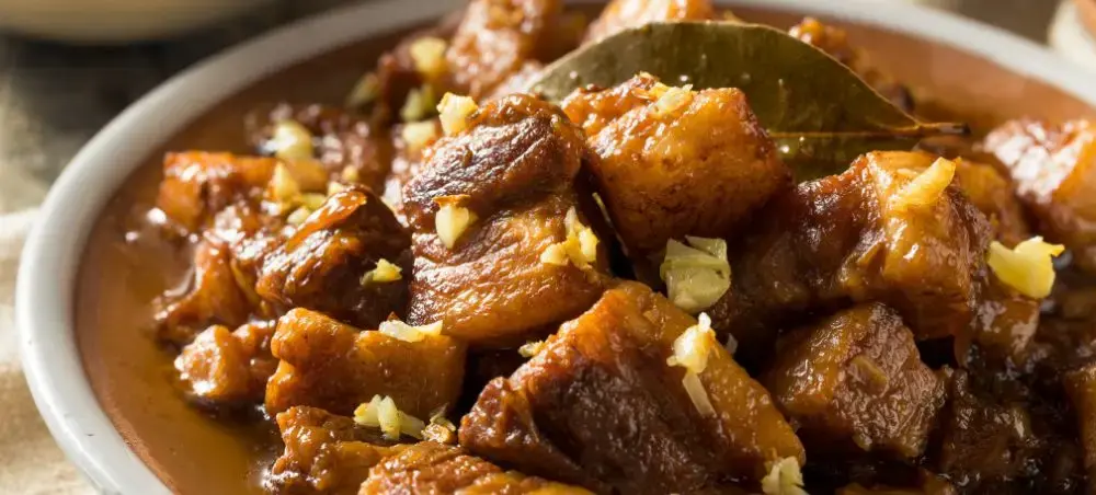 Traditional Filipino adobo pork belly with bay leaves showcasing authentic Philippine cuisine and flavors
