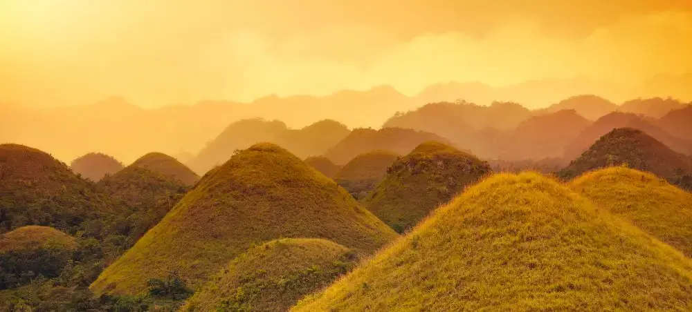 Golden sunset illuminating the iconic Chocolate Hills of Bohol, Philippines, a premier luxury travel destination