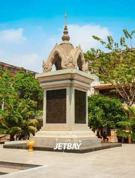 Traditional Cambodian memorial monument with ornate spire surrounded by lush greenery in Phnom Penh