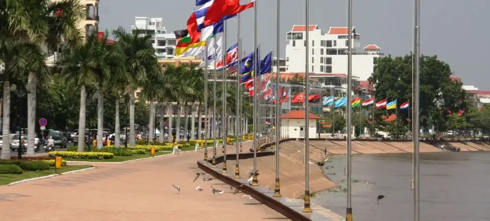 Waterfront promenade in Phnom Penh displaying colorful international flags along the Mekong River