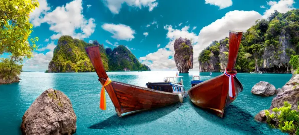 Traditional longtail boats anchored in crystal-clear waters surrounded by limestone cliffs in Phuket
