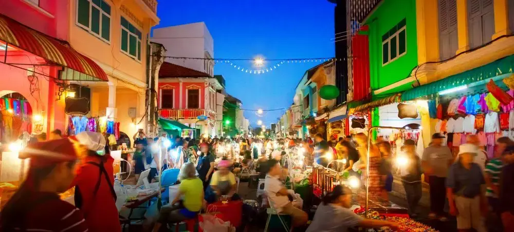Vibrant Phuket night market with colorful colonial buildings, street food vendors, and crowds exploring local cuisine