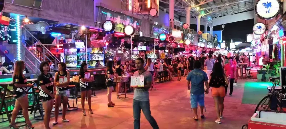 Bustling Phuket nightlife district with neon-lit bars, restaurants and crowds enjoying Thailand's vibrant entertainment scene