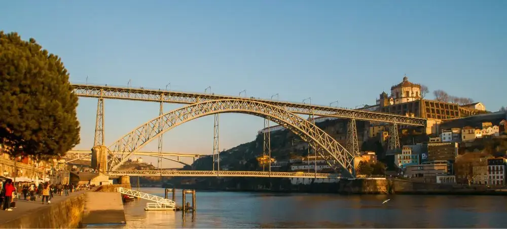 Dom Luís I Bridge spanning the Douro River in Porto at golden hour with historic riverside architecture