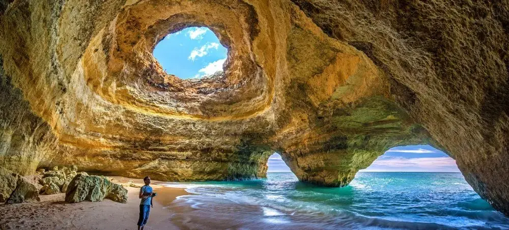 Stunning sea cave with golden limestone walls and turquoise waters along Portugal's dramatic Algarve coastline