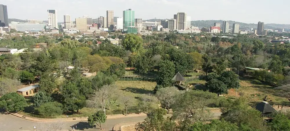 Pretoria city skyline with modern buildings rising above lush green parkland and residential areas