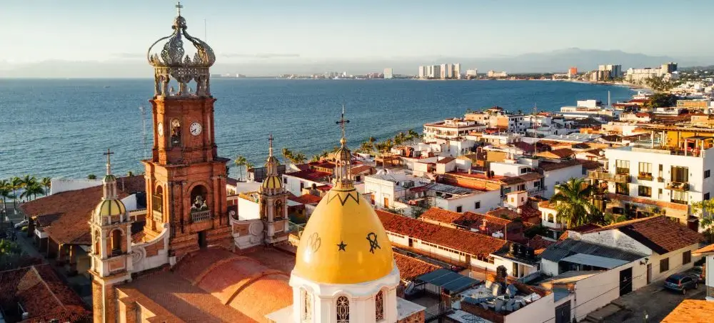 Historic Puerto Vallarta cathedral bell tower overlooking colorful colonial buildings and Pacific coastline