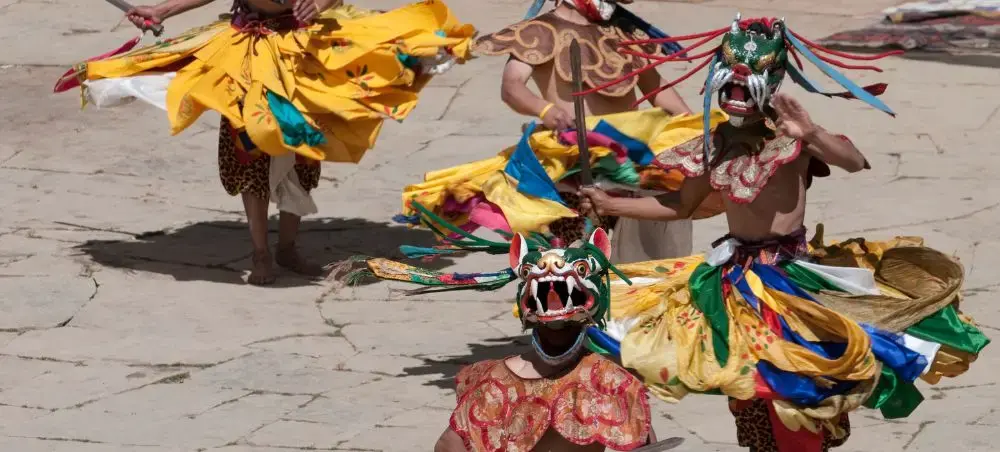 Traditional masked dancers perform vibrant Bhutanese cultural ceremony in Punakha monastery courtyard
