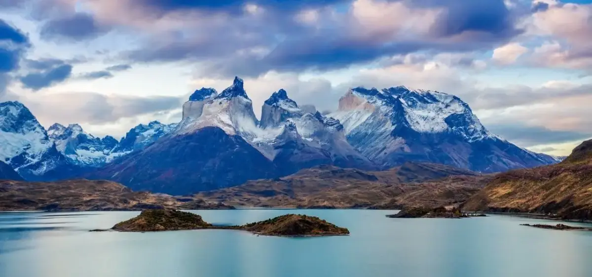 Dramatic snow-capped Torres del Paine mountains rising above pristine Patagonian lake near Punta Arenas, Chile