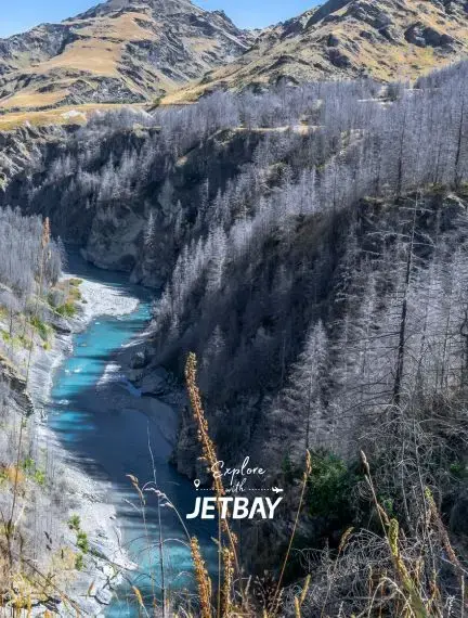 Dramatic alpine gorge with turquoise river winding through snow-dusted mountains near Queenstown