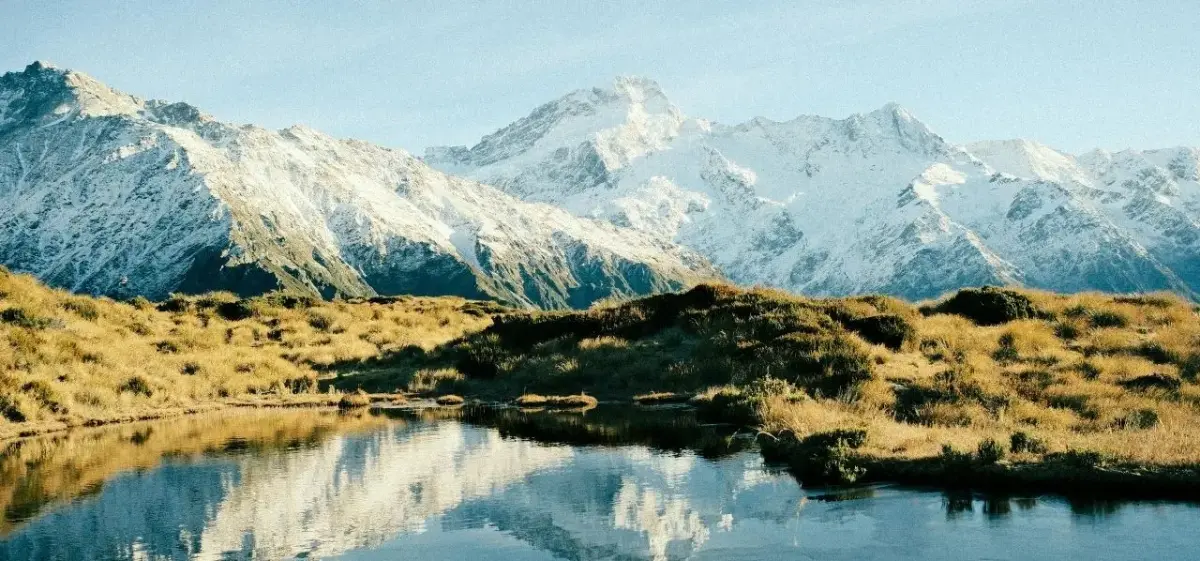 Snow-capped Southern Alps mountains reflected in pristine alpine lake near Queenstown, New Zealand