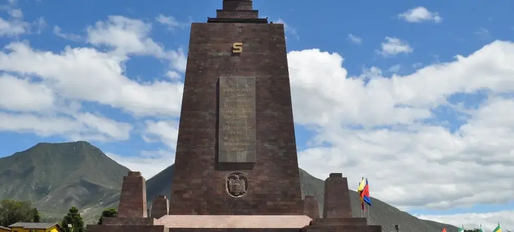Mitad del Mundo monument marking the equatorial line in Quito, Ecuador with Andean mountains backdrop