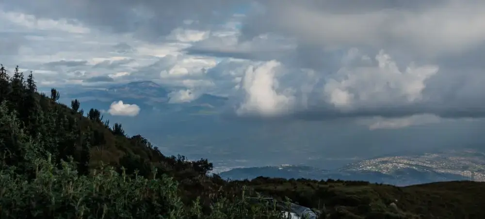 Panoramic view of Quito's mountainous landscape with rolling hills and dramatic cloudy skies over Ecuador