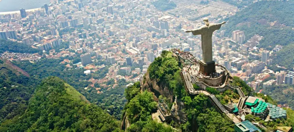 Aerial view of Christ the Redeemer statue overlooking Rio de Janeiro's sprawling cityscape and mountains