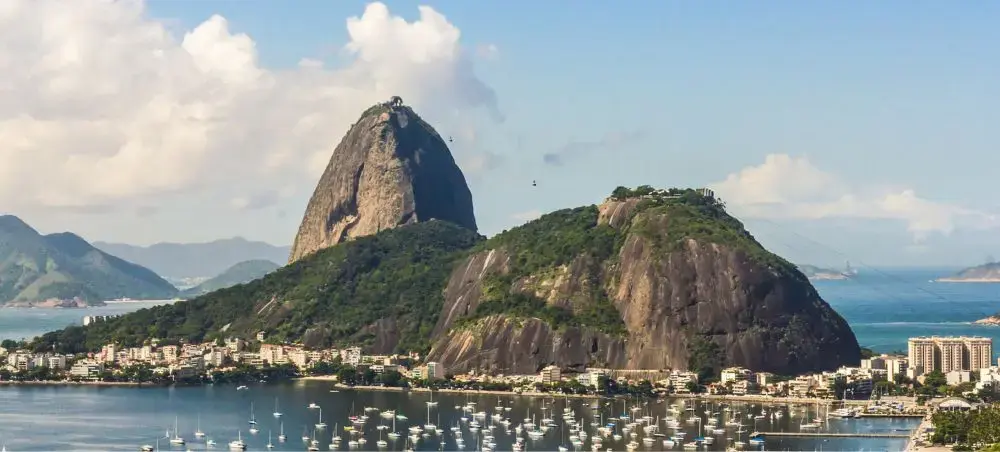 Sugarloaf Mountain rises dramatically above Rio de Janeiro's harbor with luxury yachts anchored below