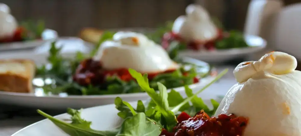 Elegant burrata cheese with arugula and sun-dried tomatoes showcasing Rome's refined culinary scene