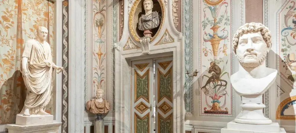 Ornate Roman palace interior with classical marble statues and frescoed walls showcasing Italy's artistic heritage