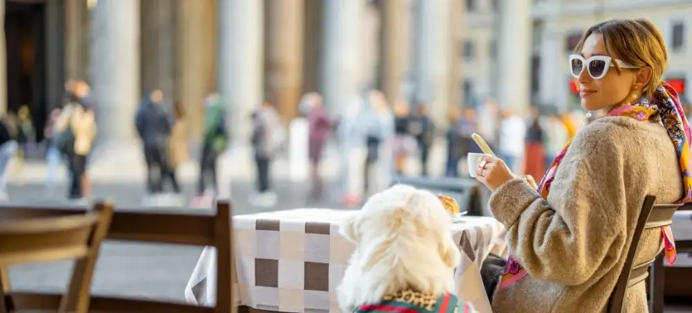 Elegant traveler enjoying coffee at outdoor cafe in Rome with classical architecture and bustling piazza