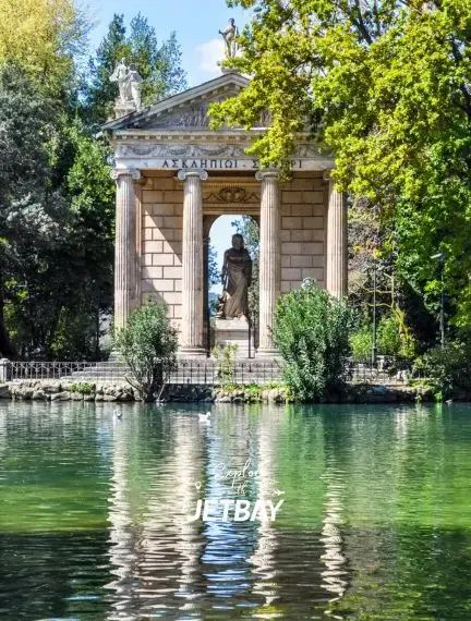 Classical temple pavilion with columns reflected in tranquil waters at Villa Borghese gardens in Rome