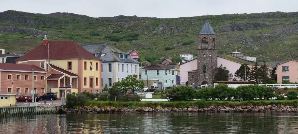 Colorful waterfront buildings and historic stone tower in Saint Pierre, showcasing the charming coastal town