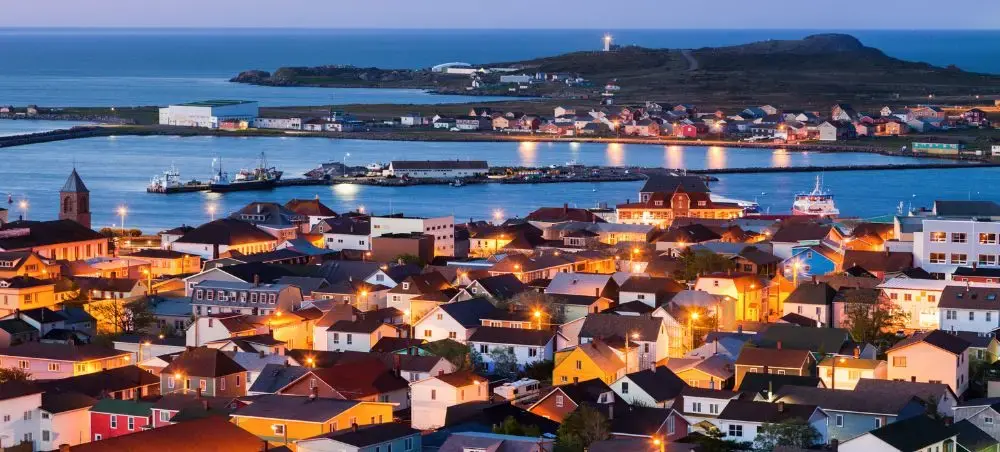 Charming Saint Pierre harbor town illuminated at twilight with colorful houses and boats in the bay