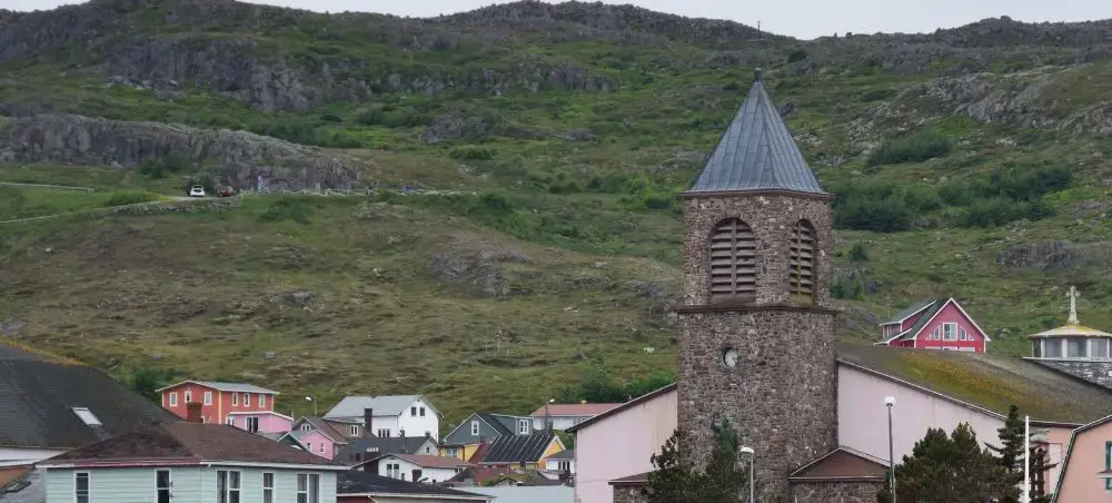 Historic stone church bell tower overlooking colorful houses in Saint Pierre's charming village center