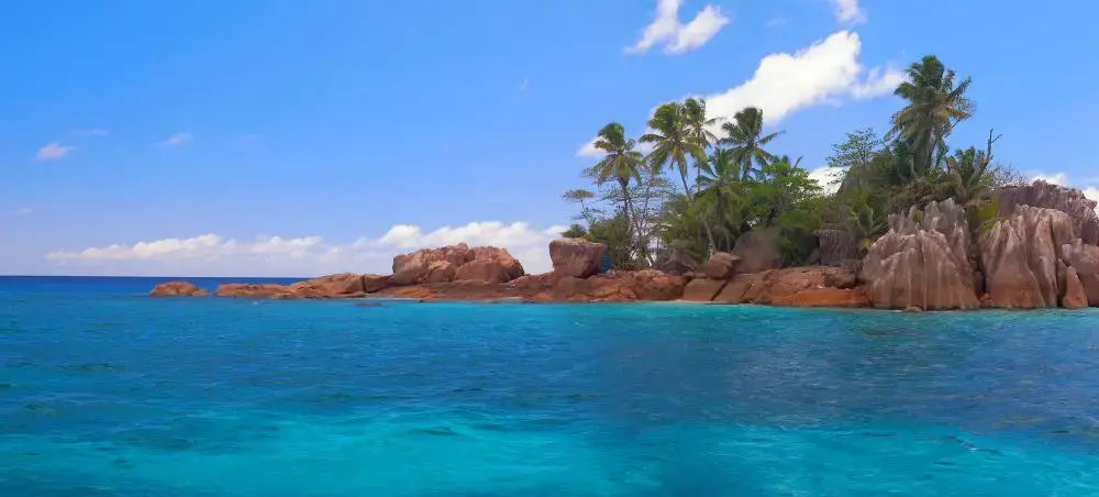 Pristine turquoise waters and granite boulders frame a tropical Saint Pierre coastline with swaying palms