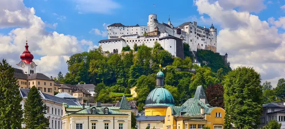 Salzburg's historic fortress Hohensalzburg dominates the skyline above baroque architecture and green hills